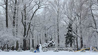 Families with a child make a snowman.