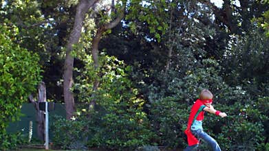 Cute boy playing super hero in the garden