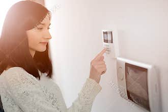 Woman entering code on keypad of home security alarm