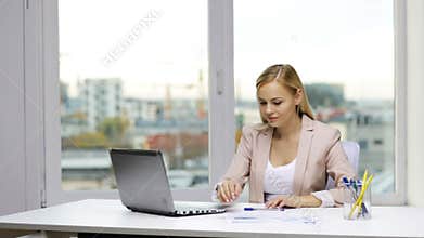 Smiling businesswoman with laptop and papers