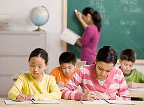Students writing in notebook in school classroom