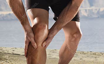 Young sport man with athletic legs holding knee in pain suffering muscle injury running