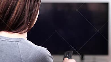 Young woman with remote control watching smart TV