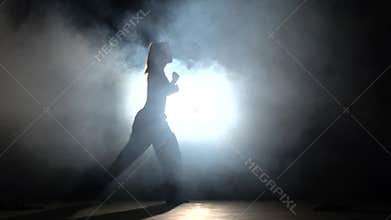 Girl with muscled body. Training martial arts. Black. Silhouette. Backlight