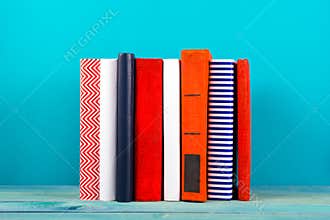 Stack of colorful books, grungy blue background, free copy space