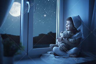 Child little girl at window dreaming and admiring the starry sky