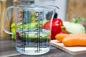1/2 Liter / 500ml / 5dl Of Water In A Measuring Cup On A Kitchen Counter With Vegetables