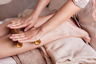 Massage of human foot in spa salon with bamboo sticks