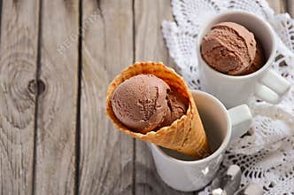 Chocolate ice cream in waffle cone on rustic wooden background