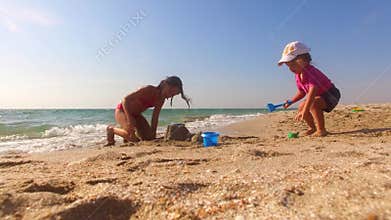 Two Children Building Sand Castle On The Beach