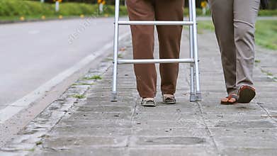 Senior woman using a walker with assistance.