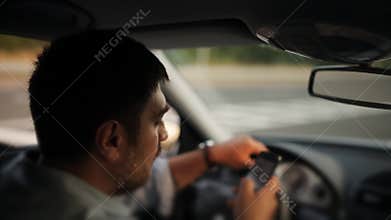 A male driver texting on a cellphone while driving
