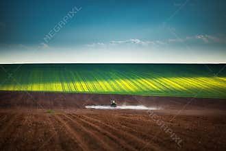 Farming tractor plowing and spraying on field