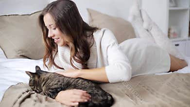 Happy young woman with cat eating in bed at home