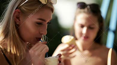 Models in bikini eating ice cream and drinking milkshakes at the outdoor cafe