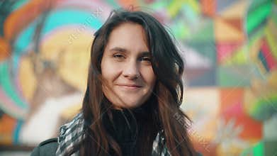 Portrait of a young smiling woman in the rays of the setting sun on a colorful background. Close-up. 4k