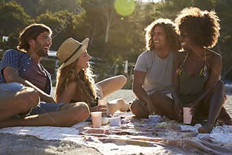 Four friends having a picnic on the beach, lens flare, Ibiza