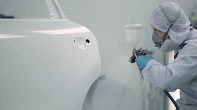 Worker sprays paint on the car door.