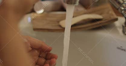 Close-up of kid's hand under stream of water in bathroom in slow motion