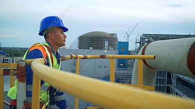 Asian engineer climbing the tower of a large oil refinery