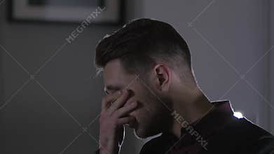 Feeling sick and tired. Frustrated young man with red pain eyes and glasses sitting at his working place in office at