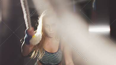 Sport girl working out with ropes in the dark gym. Slowly