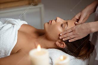 Young beautiful girl having face massage relaxing in spa salon.