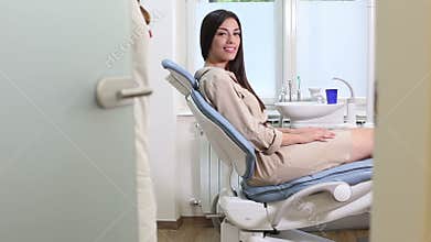 Female patient greeting dentist while sitting on dental chair