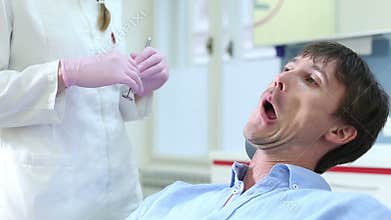 Close up of smiling male patient showing aching tooth to dentist