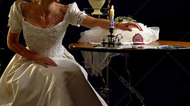 Woman in a wedding dress puts on wedding garter.
