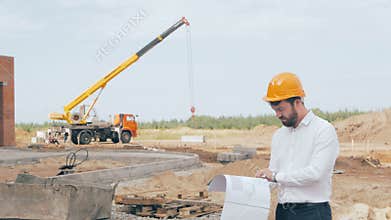 Male bearded construction boss dressed in a hard hat controls construction process.