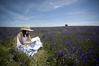 Young woman in white dress reading book outdoors