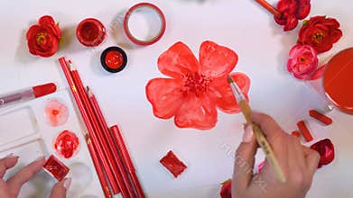Female artist hands drawing red flower. Creative artist desk from above.