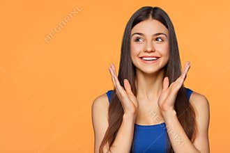 Surprised happy beautiful woman looking sideways in excitement, isolated on orange background