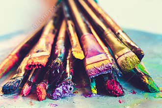 Artist paintbrushes with paint closeup on artistic canvas.