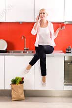 Woman sitting on counter in kitchen