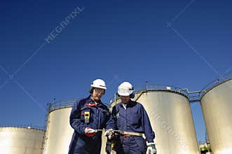 Oil workers and refinery tanks