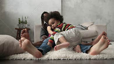 Happy interracial family sitting barefoot on floor