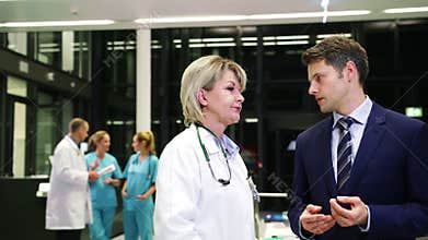 Female doctor interacting with businessman in corridor