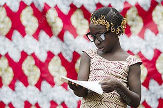 African school girl with big black glasses reading a book with blurred background