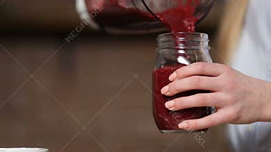 Closeup pouring beet smoothie from blender to jar