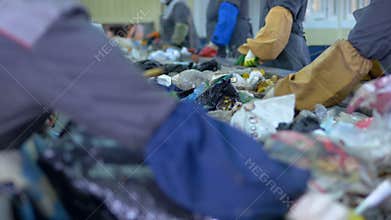 Waste recycling plant. Workers hands sorting garbage for recycling.