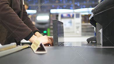 Shopper paying for products at checkout. Foods on conveyor belt at the supermarket. Cash desk with cashier and terminal
