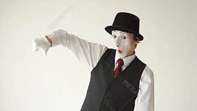Man MIME shows thumbs up and thumbs down, looking at the camera on white background