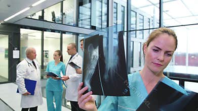 Nurse examining x-ray report in corridor