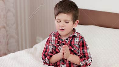Small boy praying, kid saying prayer before going to bed, strong belief in heart, boy praying to god