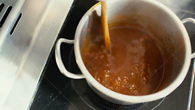 Closeup of professional chef man prepare gravy sauce with spices on oven at restaurant kitchen