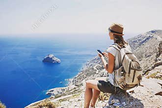 Hiking woman using smart phone taking photo, travel and active lifestyle concept