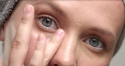 Closeup of 30`s woman`s eyes looking at camera and put an eye cream