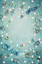 Party, carnival or birthday frame with colorful confetti and streamer on vintage blue table top view. Flat lay style. Holiday.